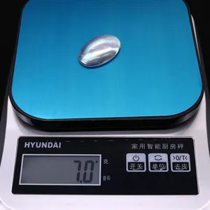 Macro shot of an oval iridescent mother of pearl shell bead on an electronic scale showing 7.0g