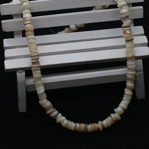 Close-up of natural shell flat round beads in mixed beige and brown on wooden prop