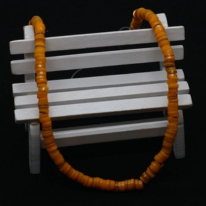 Detail of vibrant orange flat shell beads on a mini bench with a black background