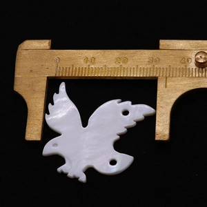 Dettaglio del ciondolo a forma di uccello in conchiglia naturale con misura della scala