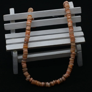 Macro shot of 5-8mm irregular pink dyed shell beads hanging on a mini white bench detail