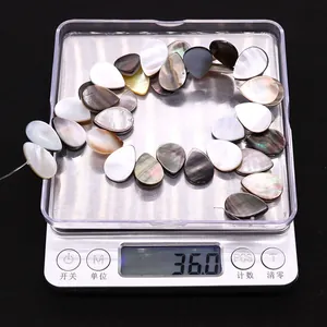 Schwarze und weiße Muschelperlen in Tropfenform auf einer Digitalwaage mit 36g