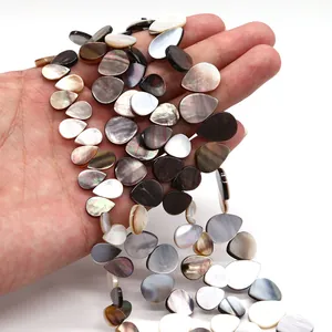 Hand hält irisierende wasserfallförmige schwarze Perlmutt Muschelperlen für DIY Schmuck