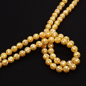 Detail of 8mm yellow mosaic shell beads with mother of pearl inlay on black background