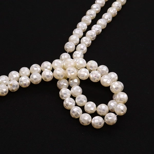 Detailed close-up of white mother of pearl beads with a square grid mosaic cutting pattern
