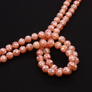 Macro detail of natural mosaic shell beads with pink-orange luster and diamond cut pattern