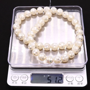 Macro shot of natural white shell mosaic beads weighing 51.2 grams on a digital scale