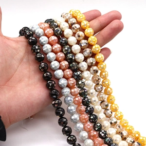 Natural mosaic shell beads in multiple colors held by hand for jewelry making
