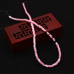 Macro shot of pink sea shell cylindrical beads placed on a vintage wooden carved box
