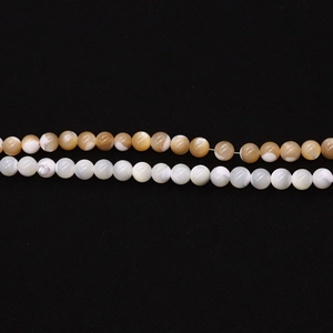 Macro shot of polished 8mm natural white and tiger-striped shell beads for DIY jewelry