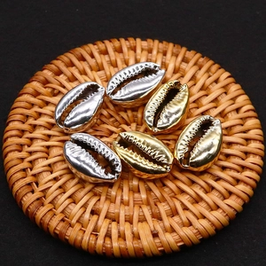 Metallische Gold- und Silbermuschelanhänger für DIY-Schmuck auf gewebter Naturmatte