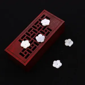 Poliertes 10mm Muschelblumen-Perlen für DIY-Schmuck auf hölzernem Hintergrund