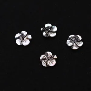 Vue détaillée de perles de nacre noire en forme de fleur à cinq pétales irisées
