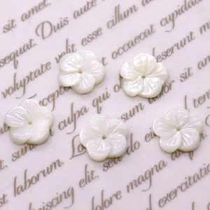 Makroaufnahme von 10mm weißen Muschelblumenperlen mit Perlglanz auf Vintage-Papier