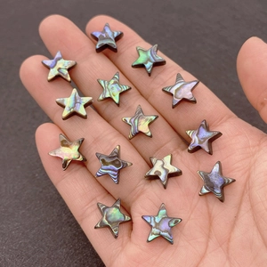 Macro shot of star-shaped abalone shell beads with iridescent glow on a hand