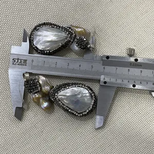 Dettaglio pendente a goccia in madreperla con perle barocche e piccoli strass lucidi