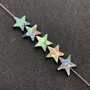 Macro detail of iridescent five-point star abalone shell beads on a thin metal wire