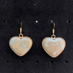 Macro detail of heart-shaped natural stone earrings with gold plated edges on velvet