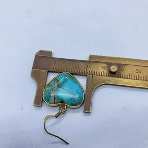 Detailed view of turquoise heart earring measured with a caliper showing 20mm width