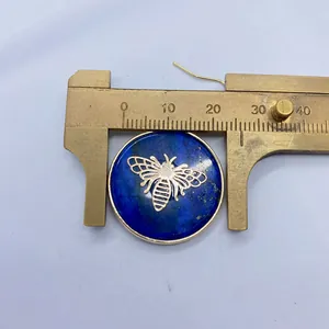 Detail view of 26mm round Lapis Lazuli stone pendant with golden bee motif on caliper