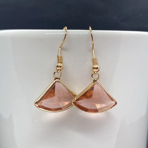 Macro shot of pink faceted crystal fan-shaped pendant with golden metal edges