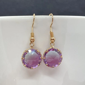 Dettaglio macro del cristallo viola sfaccettato su orecchini in filo d'oro intrecciato