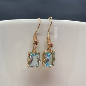 Vue détaillée des boucles d'oreilles en cristal bleu avec crochets dorés et monture ornée