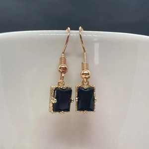 Détail de boucles d'oreilles pendantes en pierre noire avec bordure dorée vintage