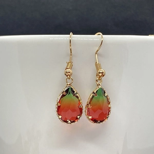 Macro detail of drop-shaped faceted crystal earrings with green to orange gradient effect