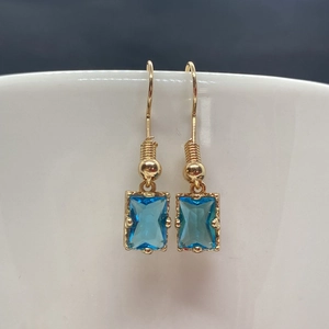 Détail de boucles d'oreilles en cristal bleu avec monture dorée sur le bord d'une tasse