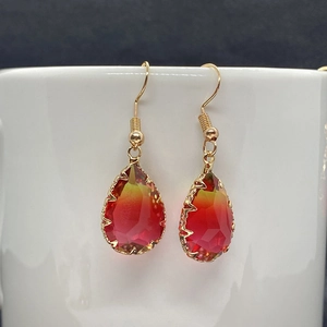 Detail of red and yellow gradient faceted crystal drop earrings with gold serrated edges