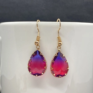 Detail of faceted teardrop crystal earrings in purple gradient with gold-plated metal hooks