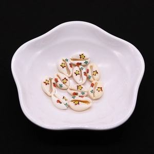 Detailed macro of 9x19mm turtle printed sea shell beads in a white ceramic dish