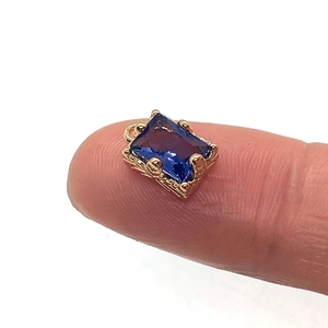 Pendentif rectangle en cristal bleu facetté avec monture dorée sur le bout du doigt