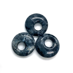 Macro detail of three natural labradorite flat round stone donuts with polished textures