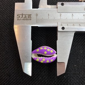 Macro shot of 18mm purple seashell bead with yellow dots measured by a digital caliper
