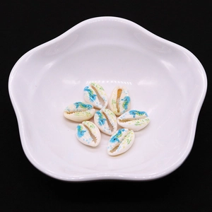 Detail of hand-painted seahorse patterns on natural cowrie shell beads for DIY jewelry making