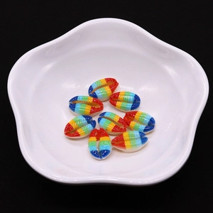 Dettaglio macro di otto conchiglie di ciprea striate arcobaleno su un vassoio bianco a petalo