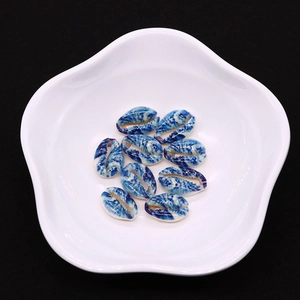 Detailansicht von 10 blau-weißen Marmor-Kaurimuscheln auf einer Schale im Blumendesign