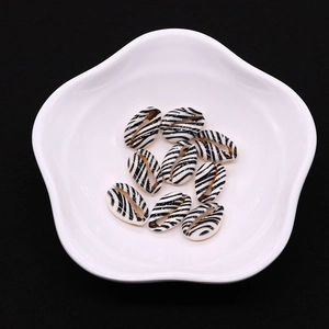 Nahaufnahme von Zebra-Naturmuscheln auf Keramikteller für DIY-Schmuckherstellung und Basteln