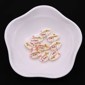 Macro shot of natural cowrie shell beads with hand-painted hearts and I Love You letters