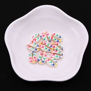 Macro detail of colorful spiral conch shell beads with vibrant V-pattern stripes on white plate