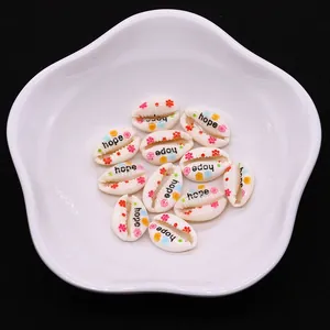 Macro detail of natural cowrie shells with floral prints and Hope text in a ceramic dish