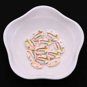 Detailed view of cream shell-shaped charm with happy text and floral patterns