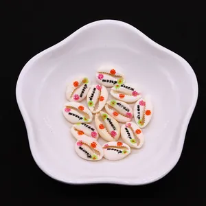 Macro view of dream letter printed natural shell charms in white petal ceramic dish
