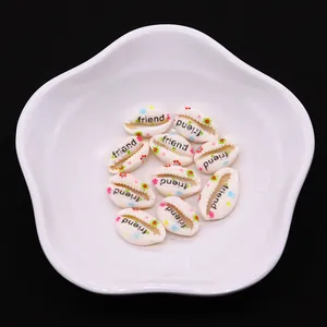 Macro detail of natural seashell pendants with colorful floral print and friend lettering