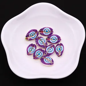 Detailed view of conch shell evil eye beads with purple stripes on a white dish