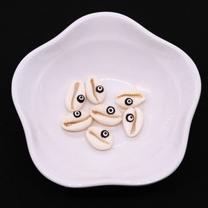 Dettaglio macro di perle in conchiglia naturale con motivo Evil Eye in un vassoio bianco