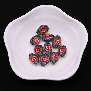 Macro detail of colorful hand-painted evil eye sea shell beads on a white ceramic plate