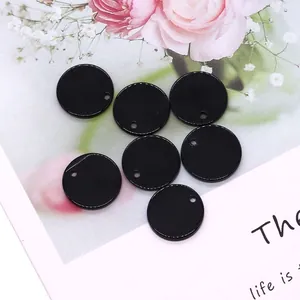 Détails macro de pendentifs ronds noirs en coquillage de 15mm sur fond floral